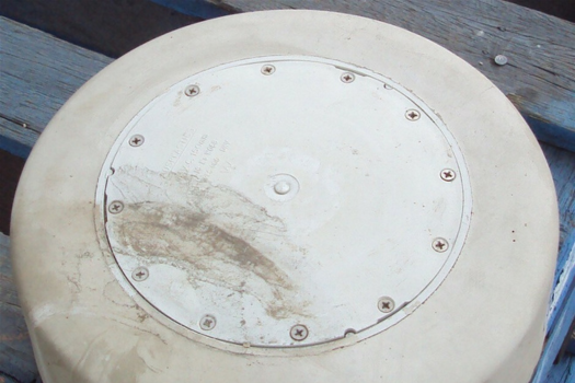 Sewer shaft with white plastic lid surrounded by concrete