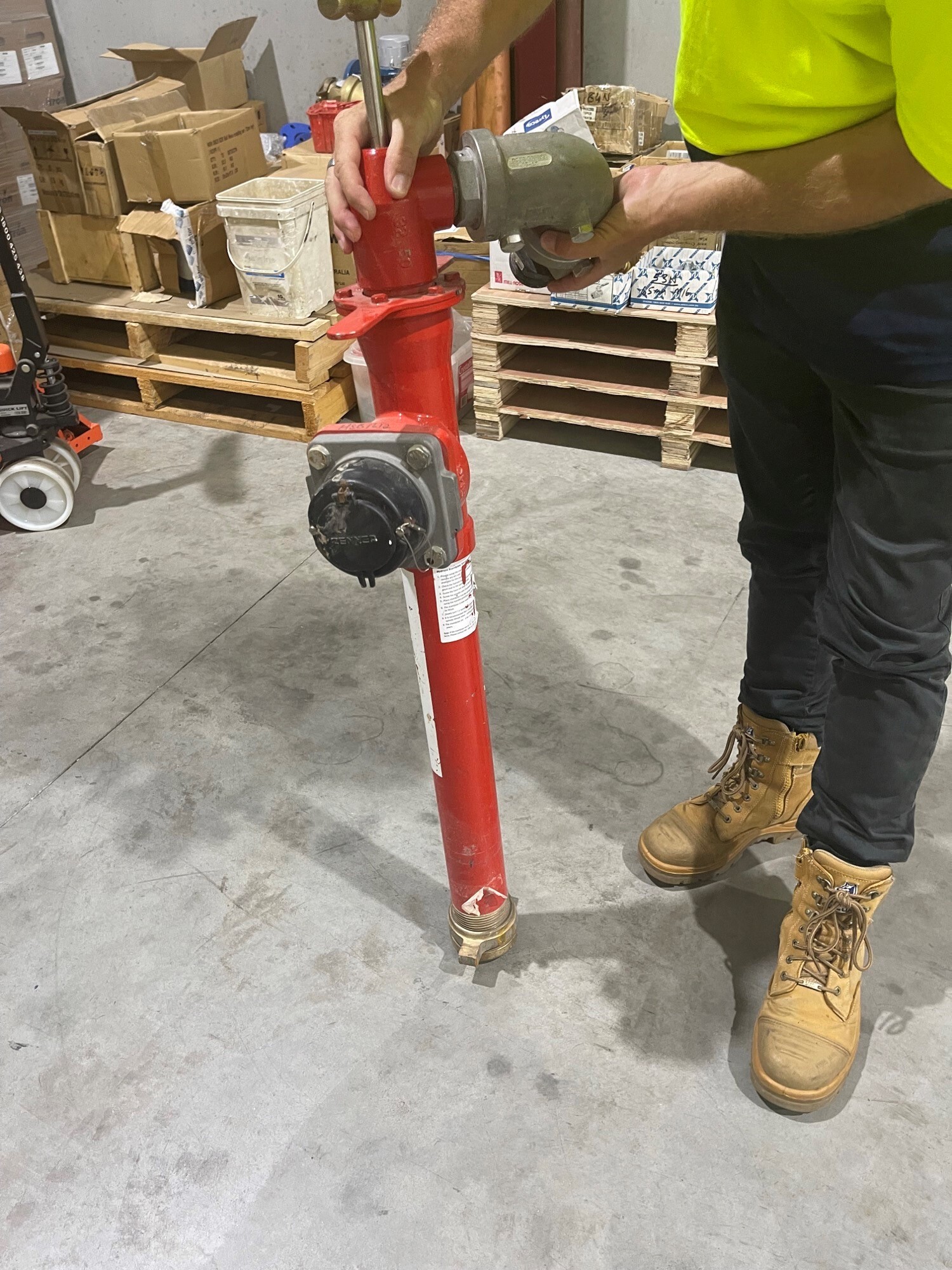 Image shows a person holding a standpipe, which is a long red metal pipe which allows water to be controlled as it flows through it
