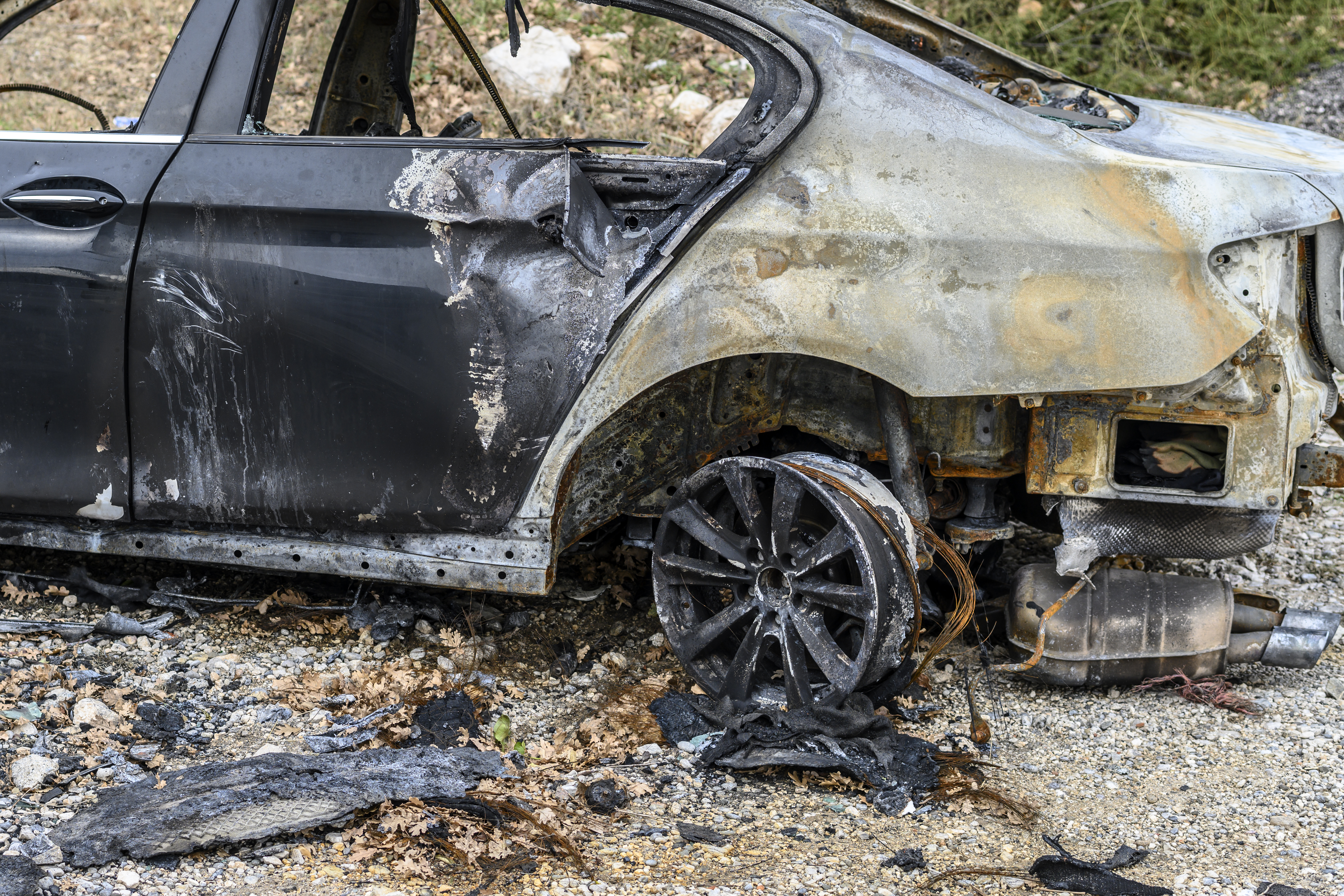 Image shows the back of a car which has been burnt and damaged as the result of a fire