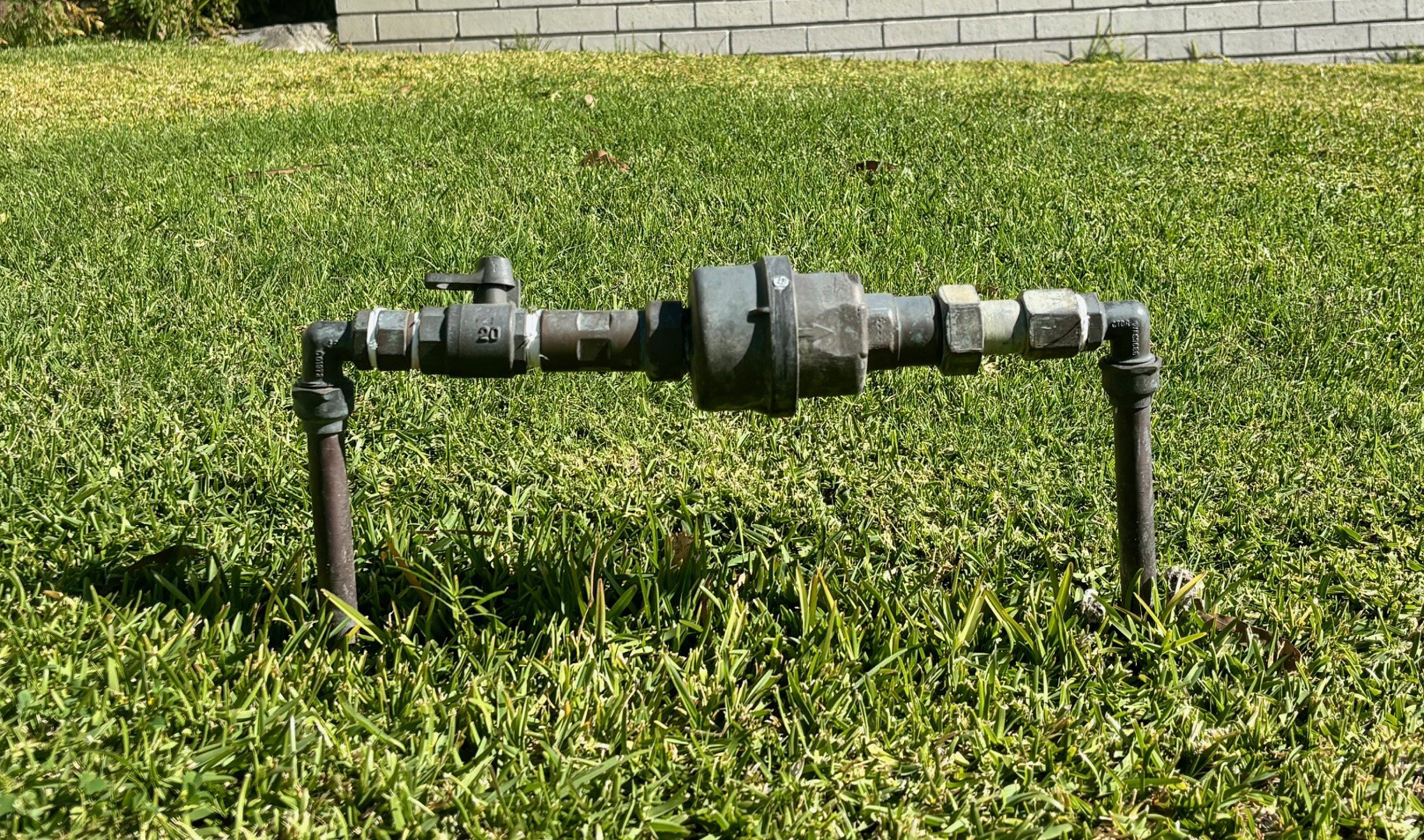 A water meter in the front yard of a property with grass around it showing it is accessible for our maintenance crew to access.